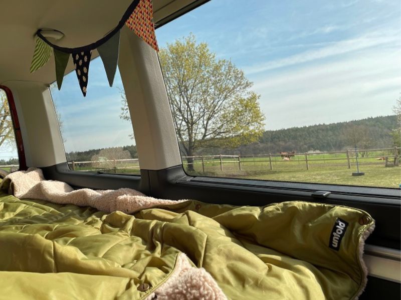 Camping-Decke im Bulli mit Stellplatz und Ausblick auf Bauernhof