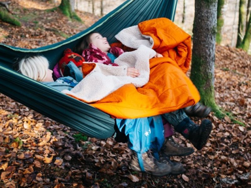 Zwei Kinder in Hängematte mit Camping-Decke